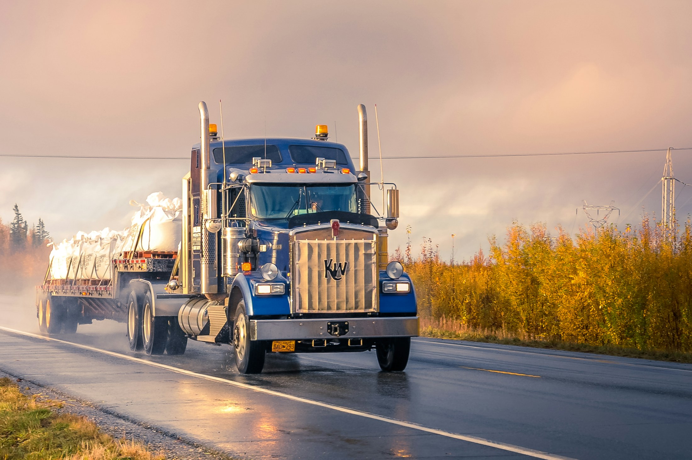 Refrigerated freight truck moving along a wet highway at dusk